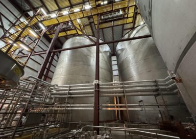 Tank room with large stainless steel storage tanks and process piping at the Elizabeth Seaport tank farm